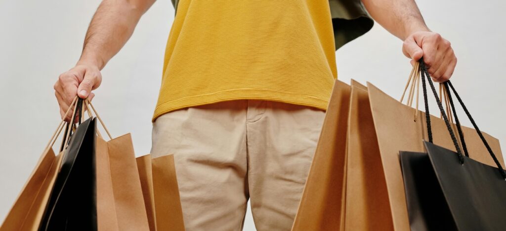 Man in Yellow Shirt and Brown Pants Holding Shopping Bags