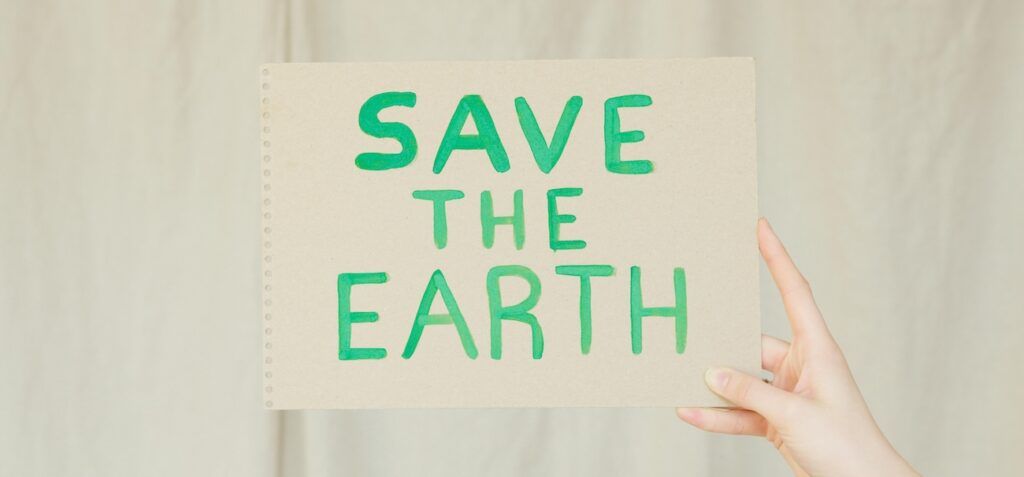 A Person Holding a Save the Earth Poster A Person Holding a Save the Earth Poster