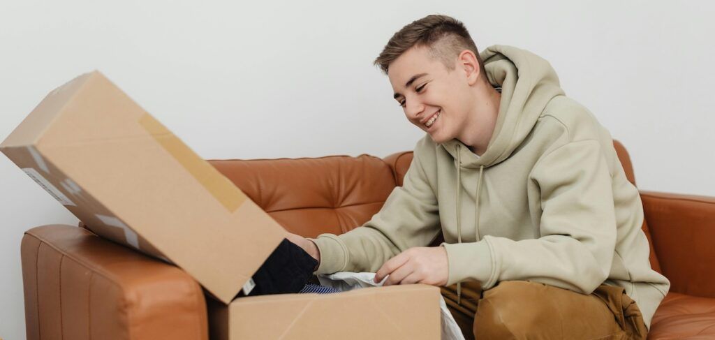 Man Sitting on a Couch Smiling While Unboxing Stuff