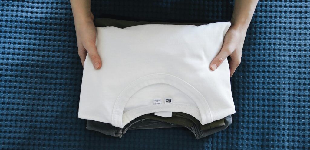 a woman folding a white shirt a woman folding a white shirt