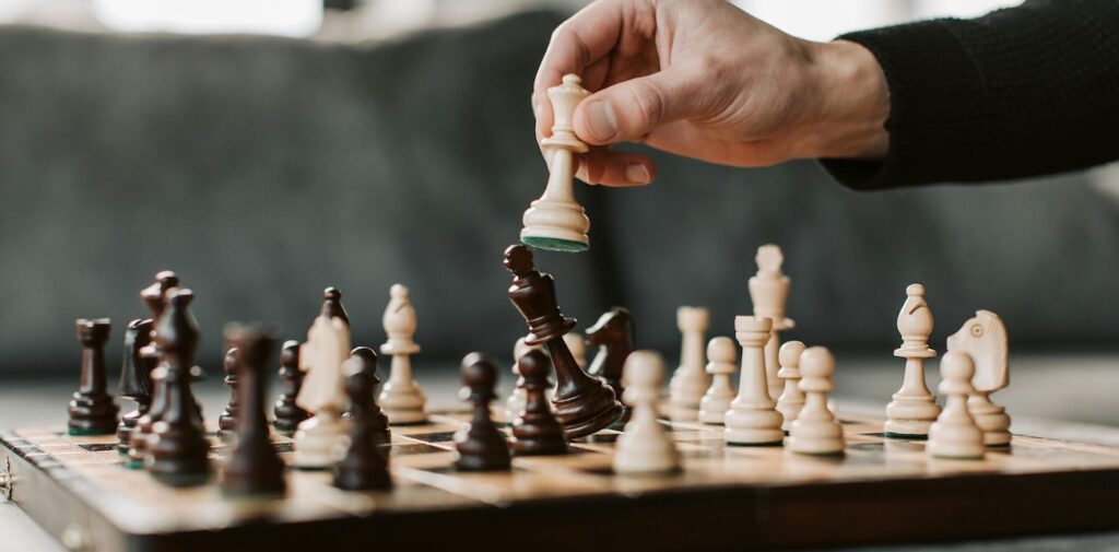 close-up of a hand moving a chess piece on a chessboard