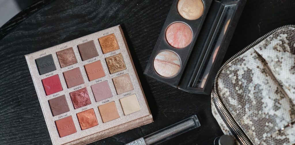 Flat lay of colorful eyeshadow palette and makeup tools on black surface Flat lay of colorful eyeshadow palette and makeup tools on black surface