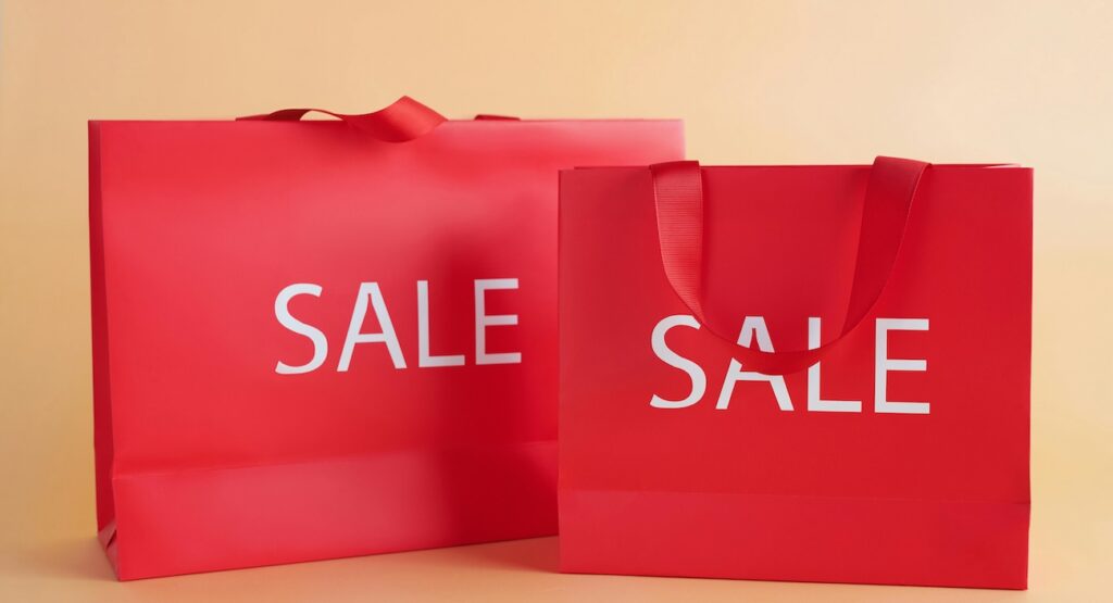 red shopping bags on a neutral background with a sale text red shopping bags on a neutral background with a sale text