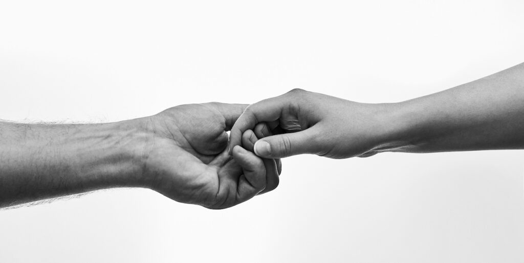 Black and white photo of two hands connecting Black and white photo of two hands connecting