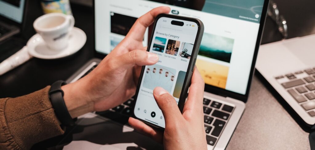 Close-up of hands using a smartphone over a laptop Close-up of hands using a smartphone over a laptop