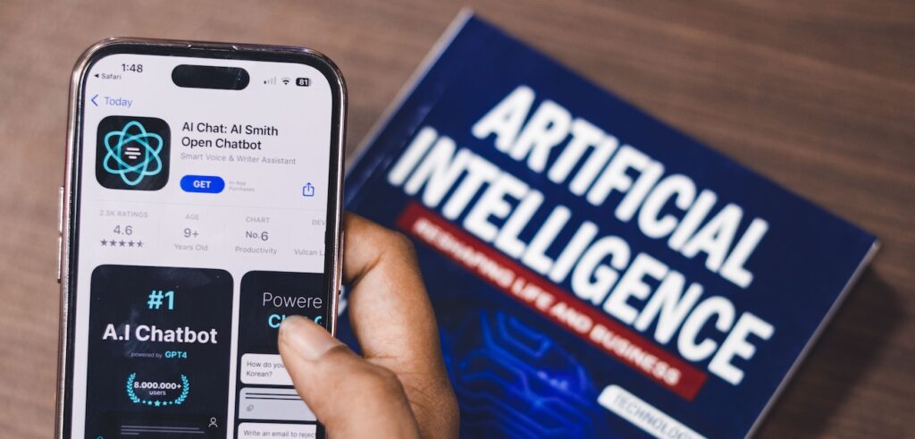 Smartphone displaying AI app with book on AI technology Smartphone displaying AI app with book on AI technology