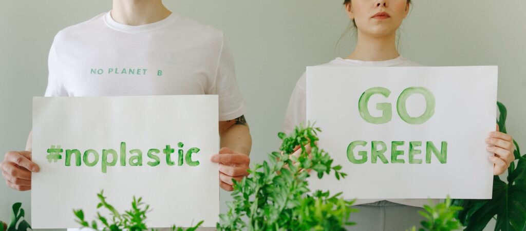 Two people holding eco-friendly signs promoting sustainability and going green Two people holding eco-friendly signs promoting sustainability and going green