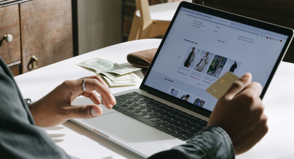 a man uses a credit card for online shopping on a laptop