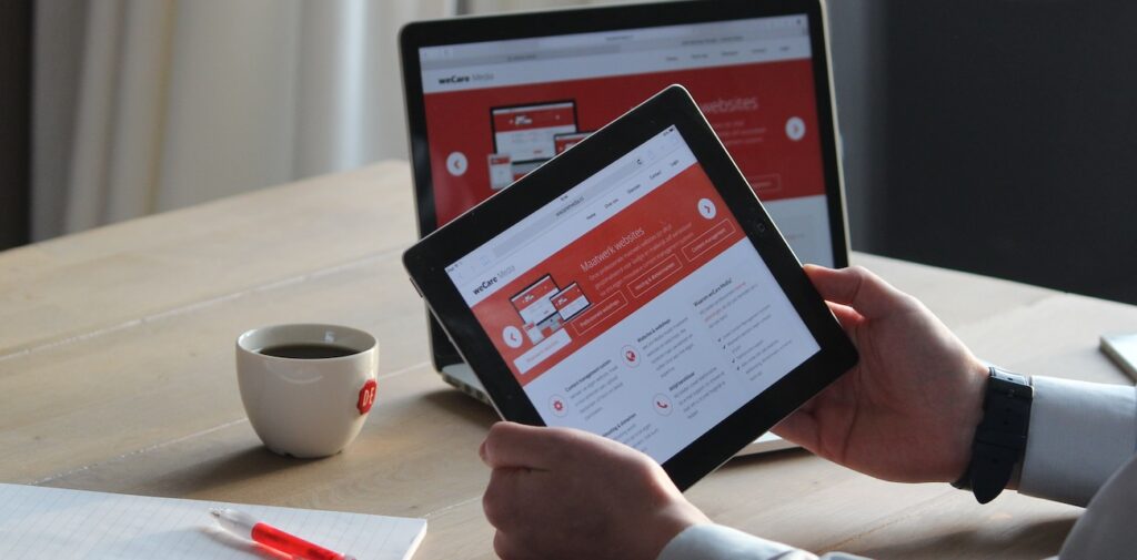 a man using a tablet and laptop with a hot drink, focusing on digital content review a man using a tablet and laptop with a hot drink, focusing on digital content review