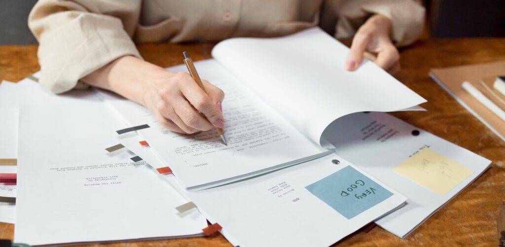 a woman writing and organizing documents on a wooden desk