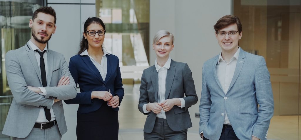Four business professionals posing confidently in a modern office environment Four business professionals posing confidently in a modern office environment