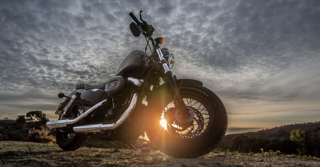 a motorcycle parked on a dirt road with a dramatic sky at sunset a motorcycle parked on a dirt road with a dramatic sky at sunset