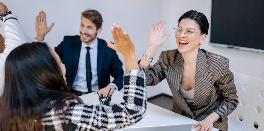 A diverse group of colleagues celebrating success with high fives in a modern office A diverse group of colleagues celebrating success with high fives in a modern office