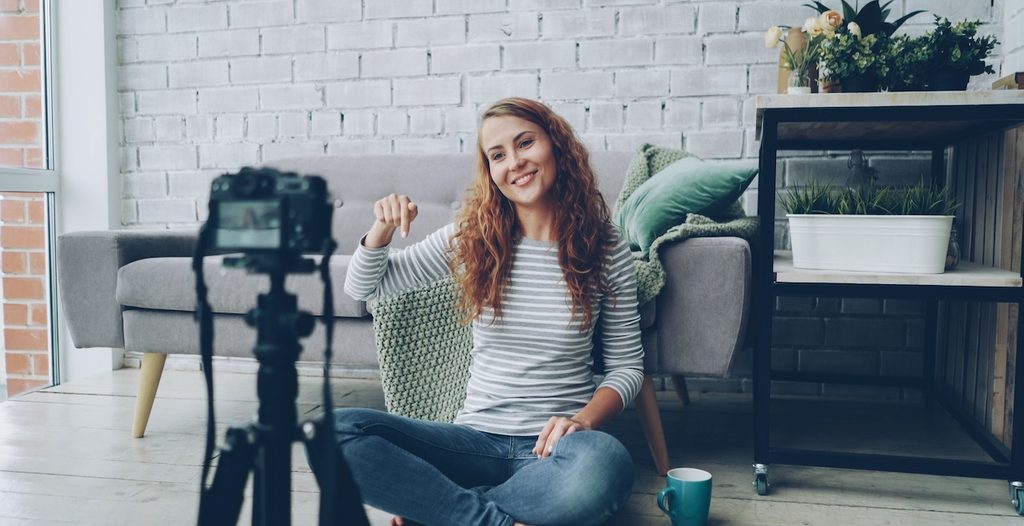 Smiling woman sitting on floor, recording video in cozy room Smiling woman sitting on floor, recording video in cozy room