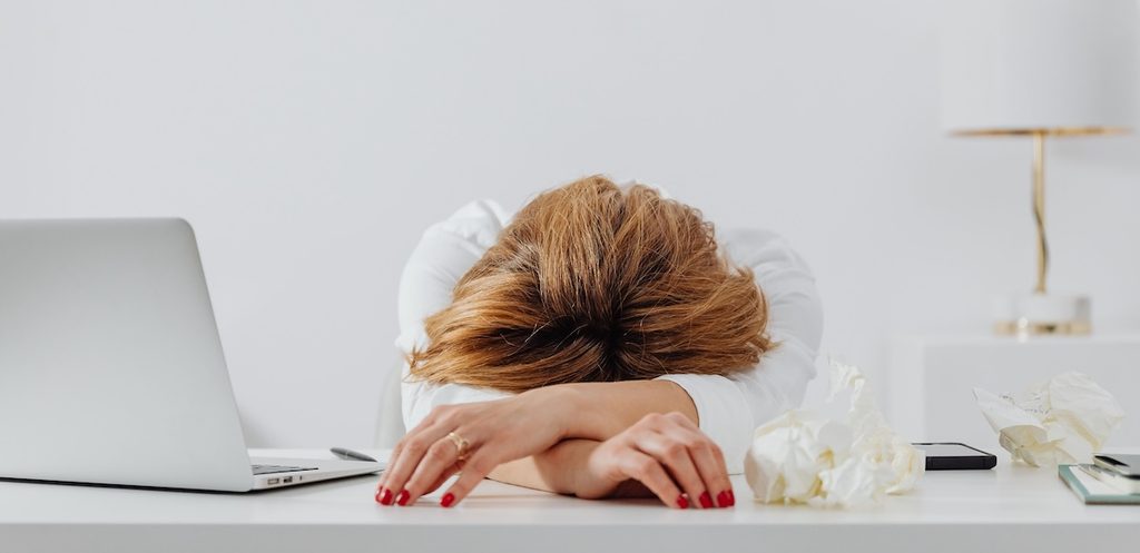 Tired woman resting head on arms at desk with laptop Tired woman resting head on arms at desk with laptop